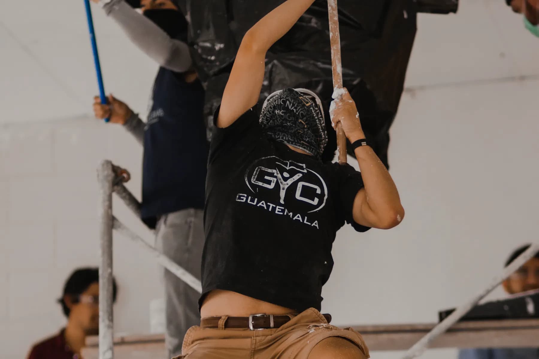 Una joven con camiseta de GYC Guatemala pintando el techo de una iglesia